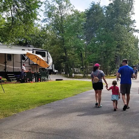 family walking on road away from camera between RV parking spots