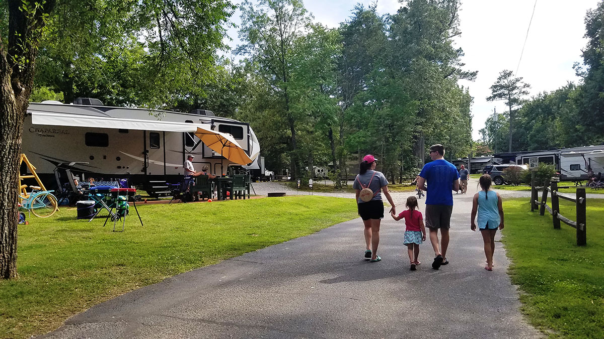 family walking on road away from camera between RV parking spots