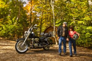 couple smiling in front of cabin with motorcycle