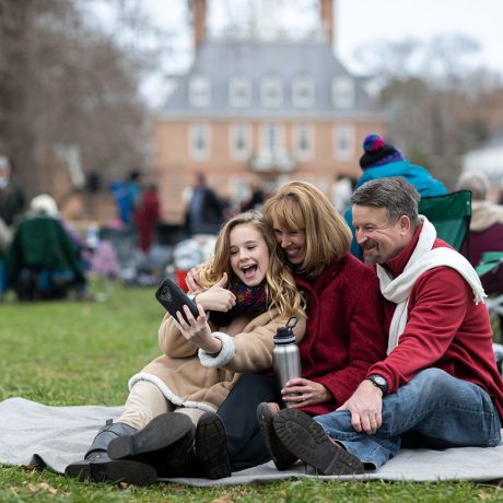 people smiling on picnic blanket in field