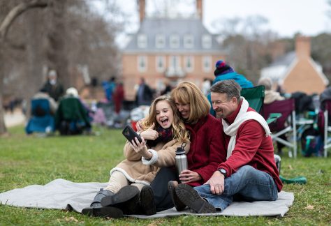 people smiling on picnic blanket in field