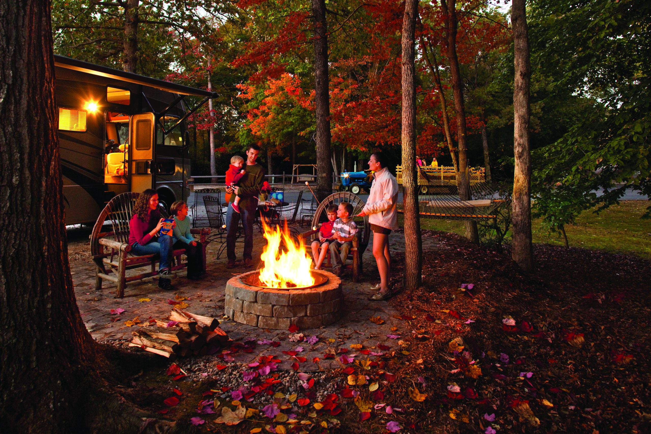 Family around a campfire with an RV in the background