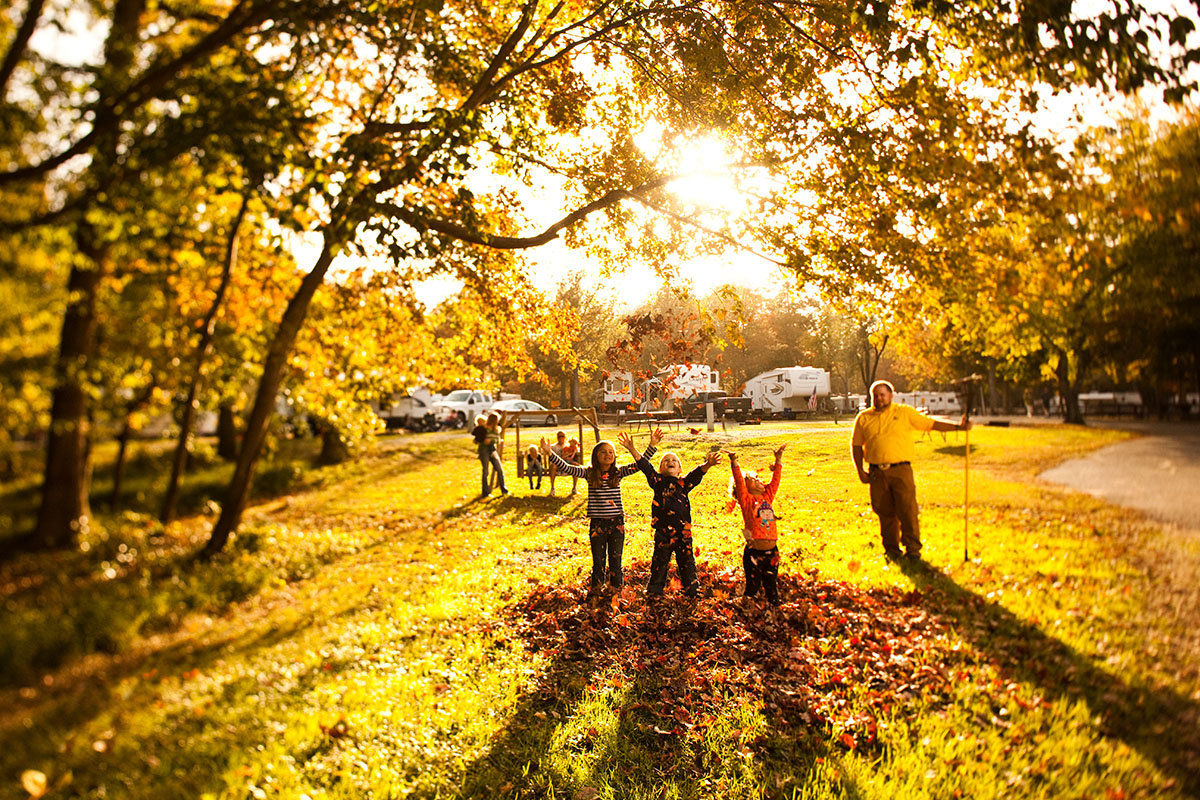 family playing in autumn leaves