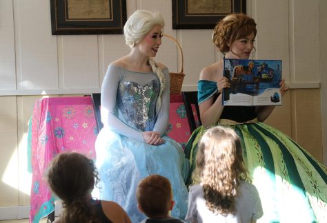 women dressed as Frozen sisters reading to children