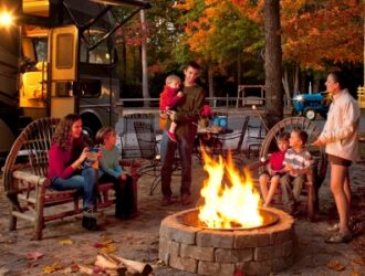 people smiling around a fire ring