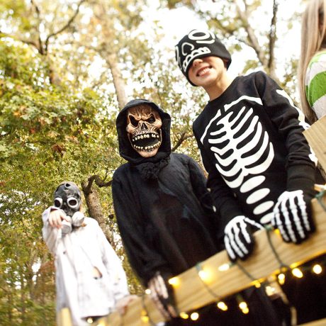 kids in halloween costumes smiling for camera with masks on