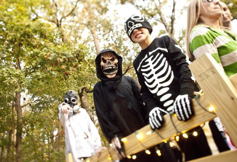 kids in halloween costumes smiling for camera with masks on
