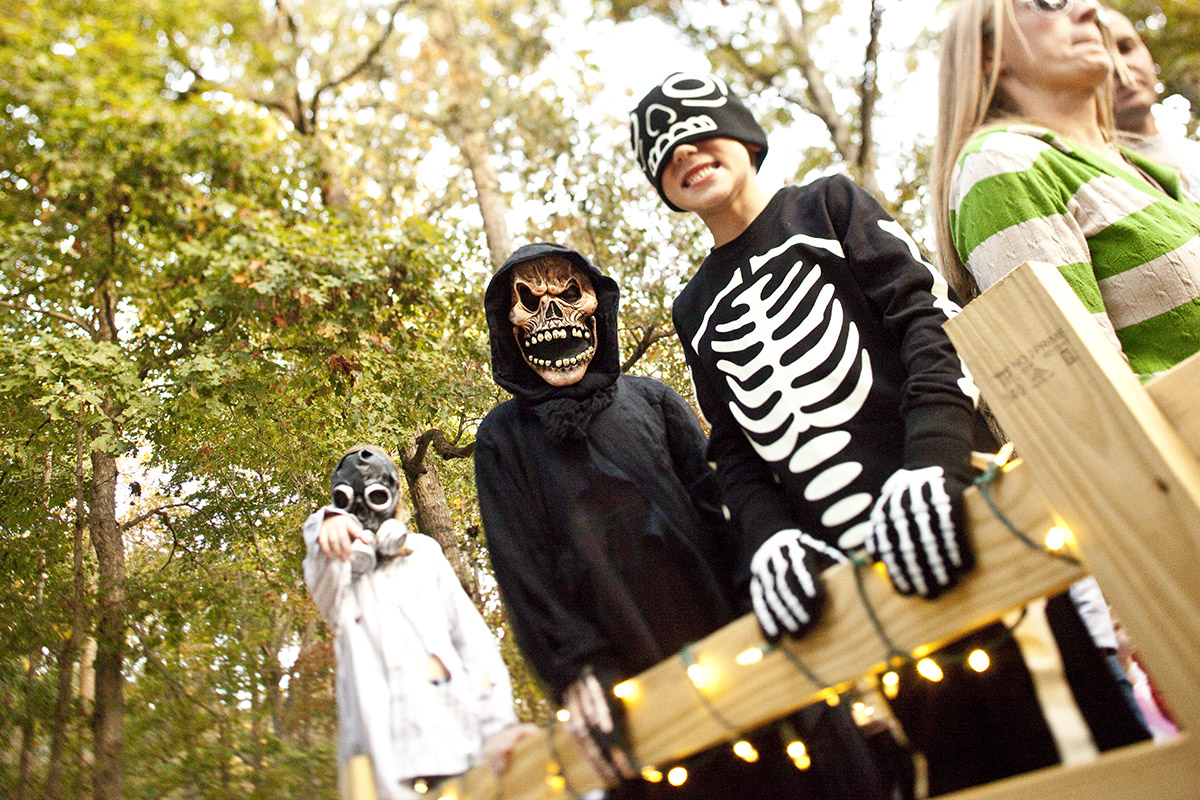 kids in halloween costumes smiling for camera with masks on