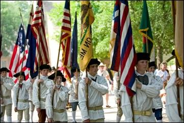 people dressed marching in uniform with flags